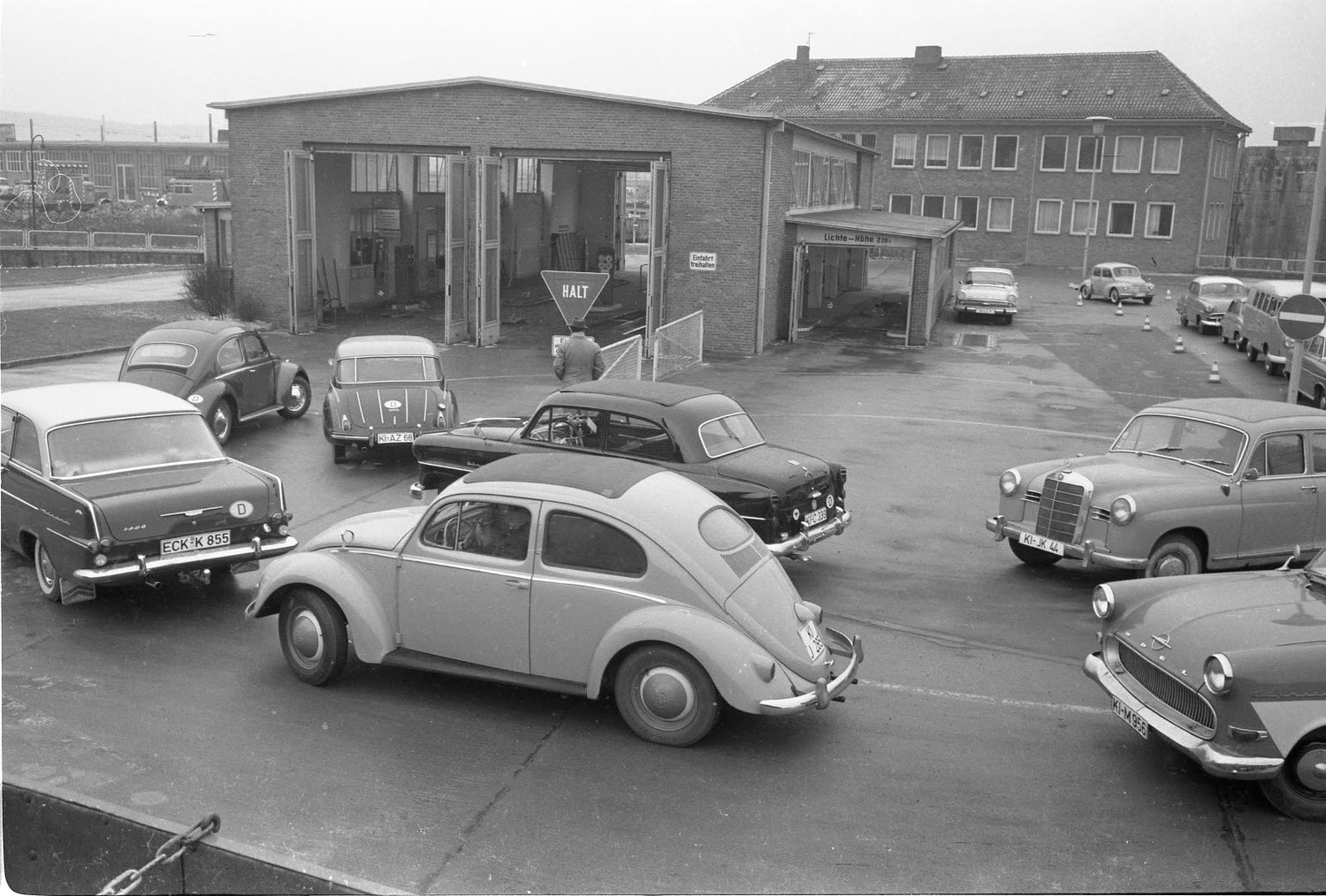 1963 stehen Autofahrer an, um eine TÜV-Plakette auf ihr Nummernschild zu bekommen.