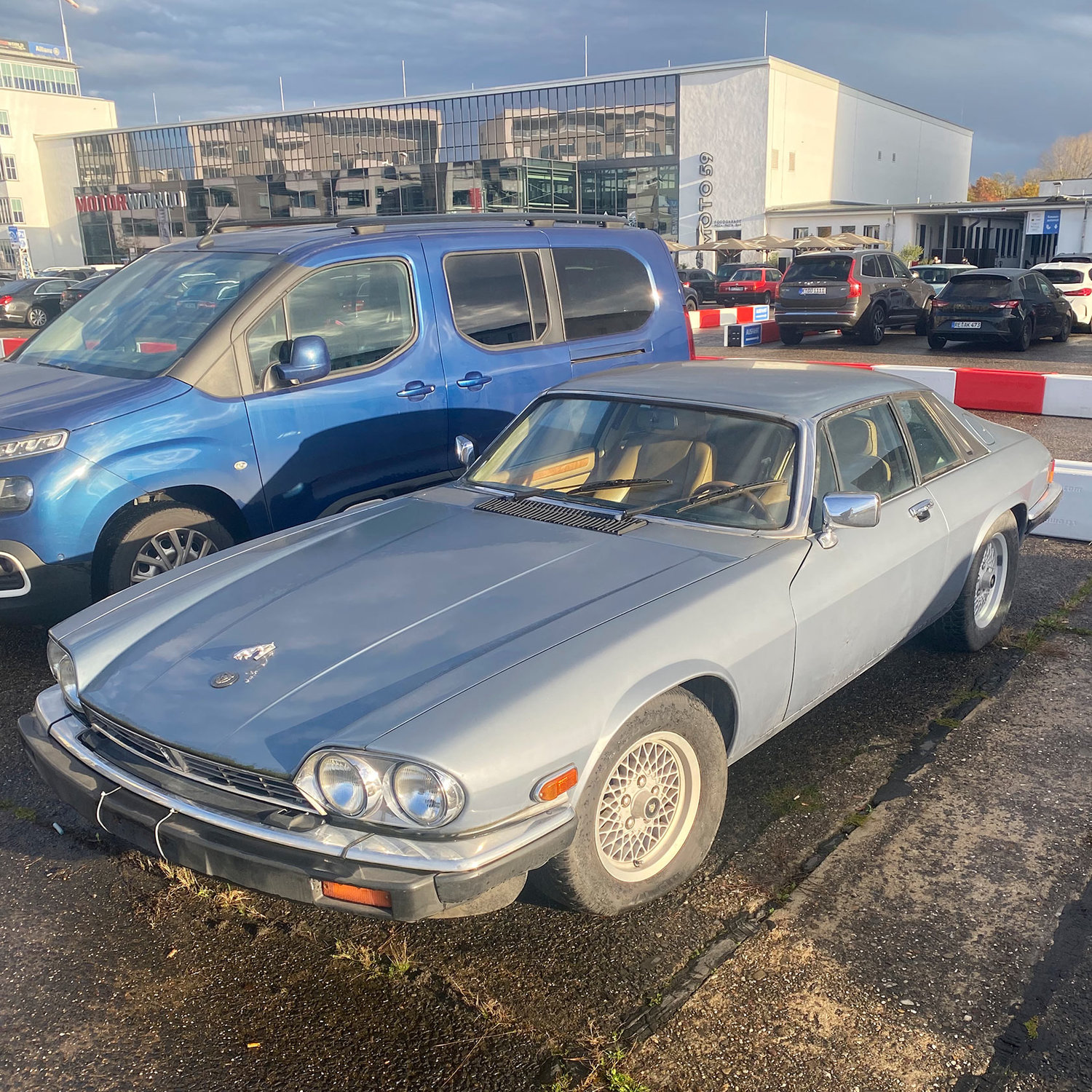 Titelbild zum Artikel:Verblasster Glanz: Der traurige Jaguar XJ-S auf dem Parkplatz 